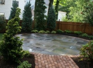 A beautiful stone and brick circular patio lead to by a brick walk, in a Maplewood NJ backyard