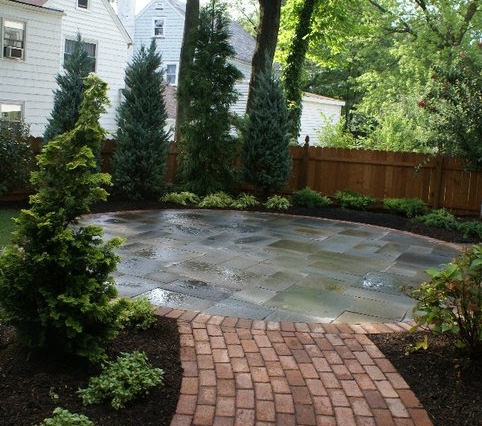 A beautiful stone and brick circular patio lead to by a brick walk, in a Maplewood NJ backyard