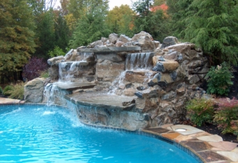 A waterfall flows into a pool in this landscape designed by GA landscape design