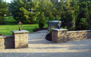 Paver wall with Columns and Lighting complete the entrance to the hot tub in this landscape